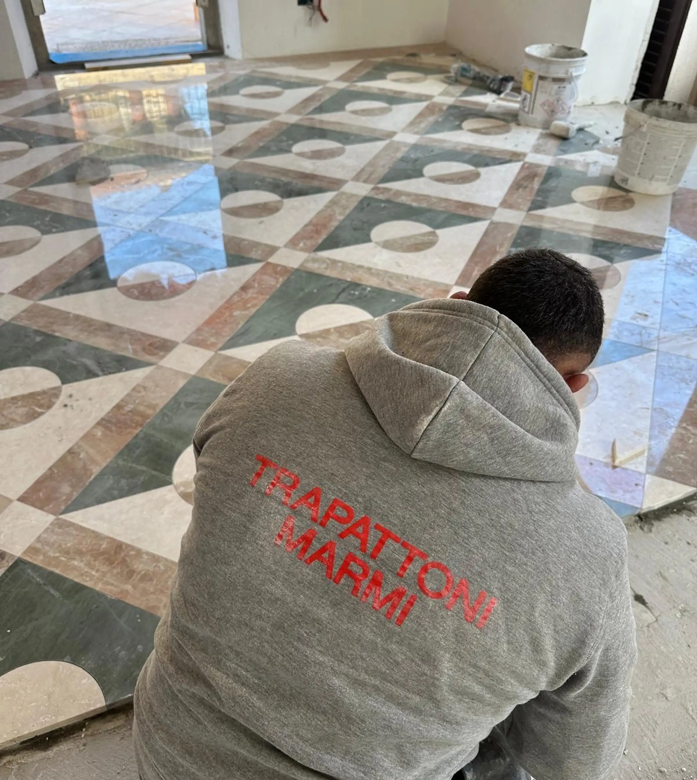 Artigiano Trapattoni Marmi durante la posa in opera di un pavimento decorativo in marmo multicolore con motivi geometrici – lavorazione artigianale marmi Bergamo dal 1967
