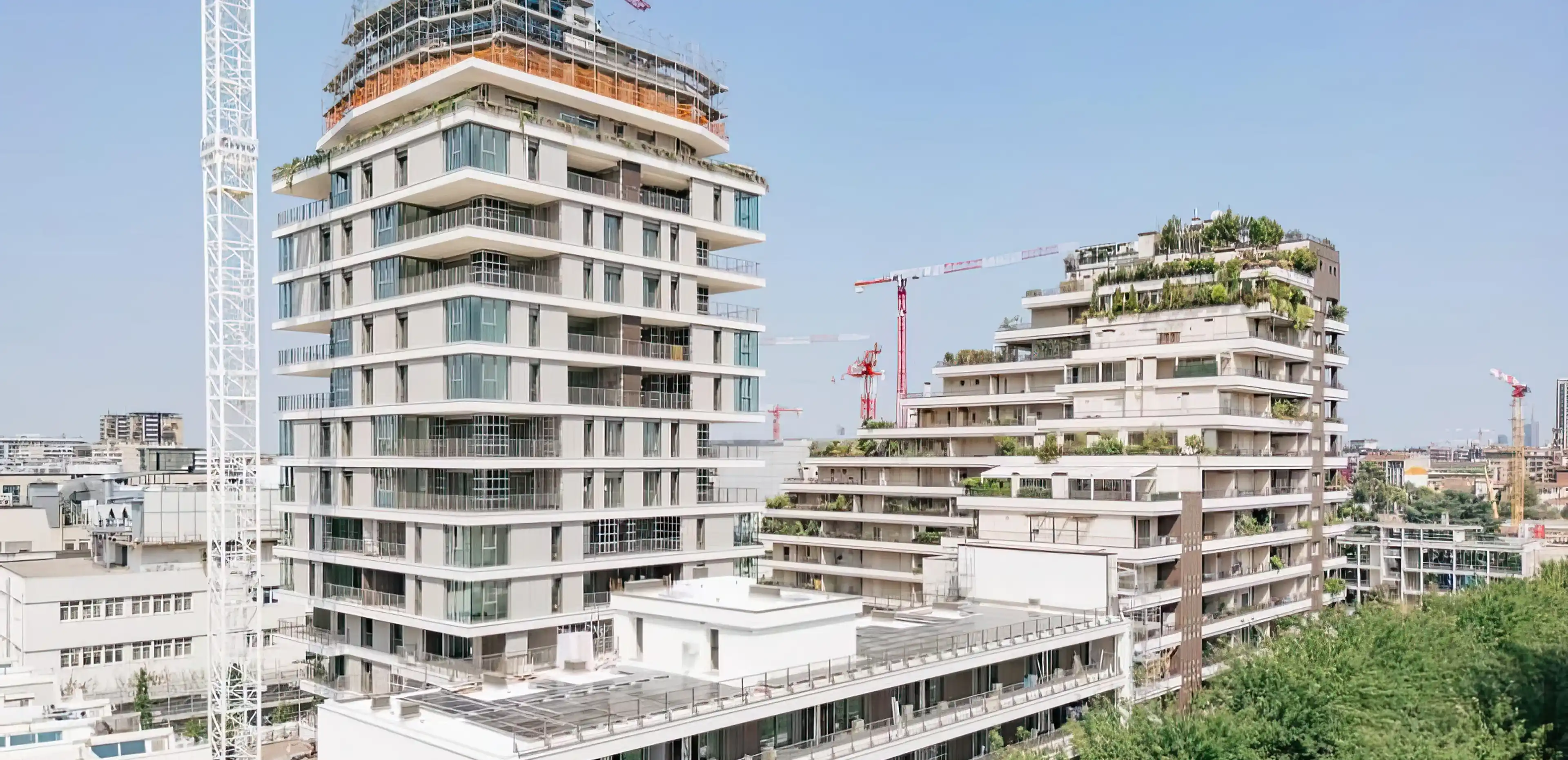 Cantiere del complesso residenziale Adamello a Milano in fase di realizzazione: torre principale e corpo basso con rivestimento di facciata in Agglotech SB130 Aggloceppo levigato e terrazze con vegetazione - posa in opera Trapattoni Marmi