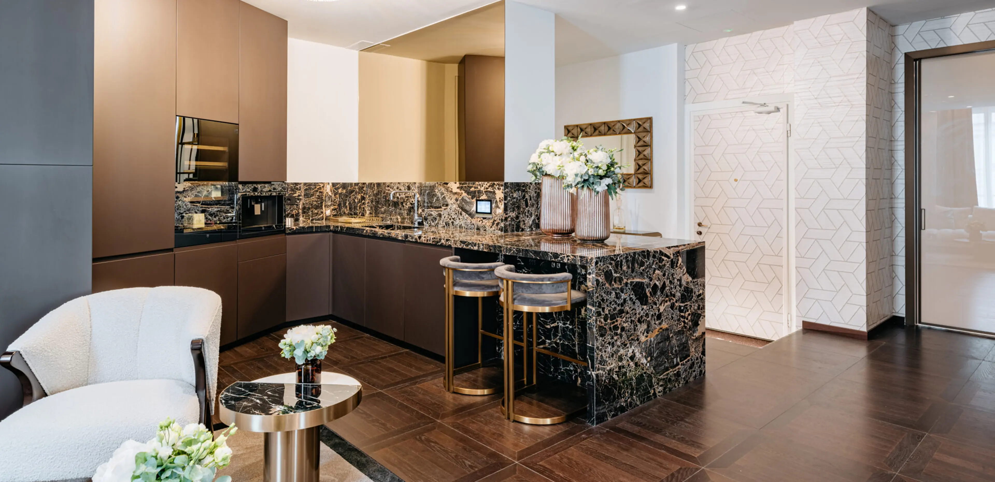 Cucina open space con isola e top in Portoro nero e oro, piano cottura e backsplash in Portoro con sgabelli in velluto grigio e ottone - tea station dello studio dentistico Pinzuti a Milano, lavorazione artigianale Trapattoni Marmi