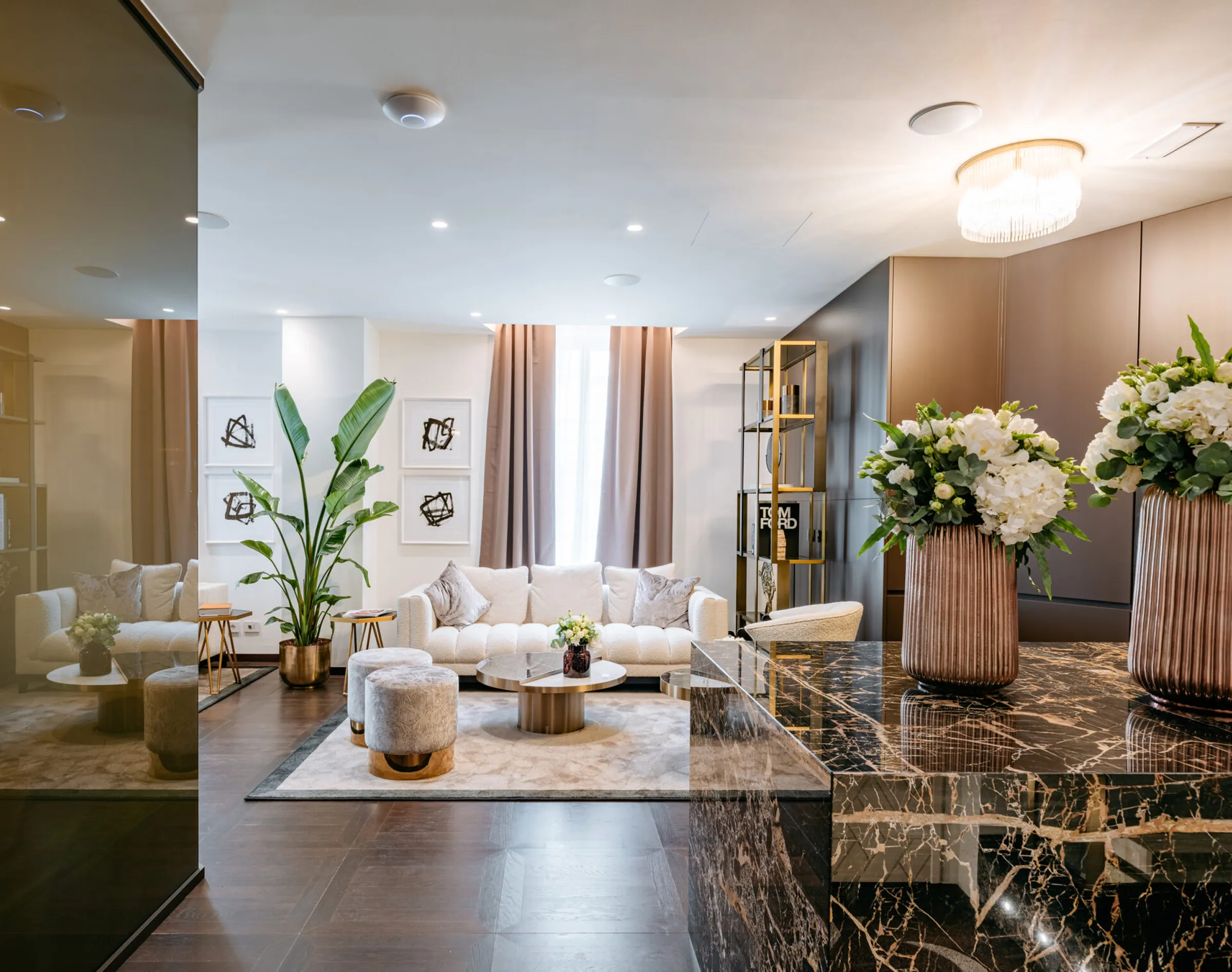 Vista sull'area relax dello studio dentistico Pinzuti a Milano: divano bianco, pouf in tessuto, piano in Portoro in primo piano e mensola con decori dorati - progetto luxury vicino al Duomo, Trapattoni Marmi