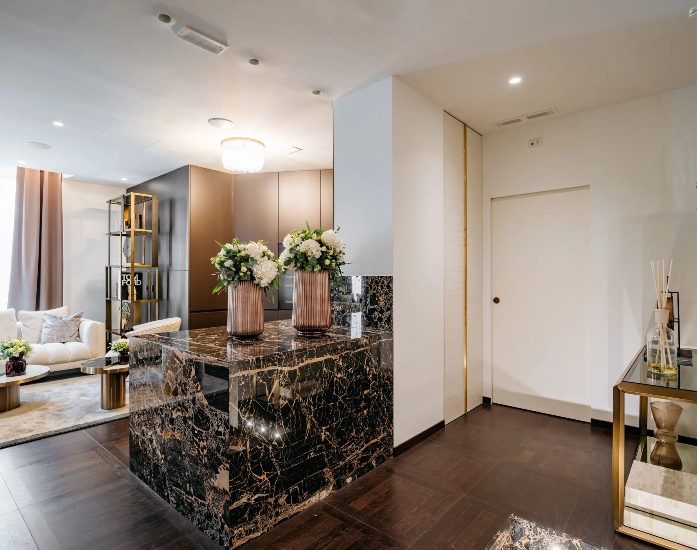 Elemento architettonico e mensola in Portoro con vasi in rame e fiori bianchi nell'ingresso dello studio dentistico Pinzuti a Milano - produzione artigianale e posa in opera Trapattoni Marmi Bergamo