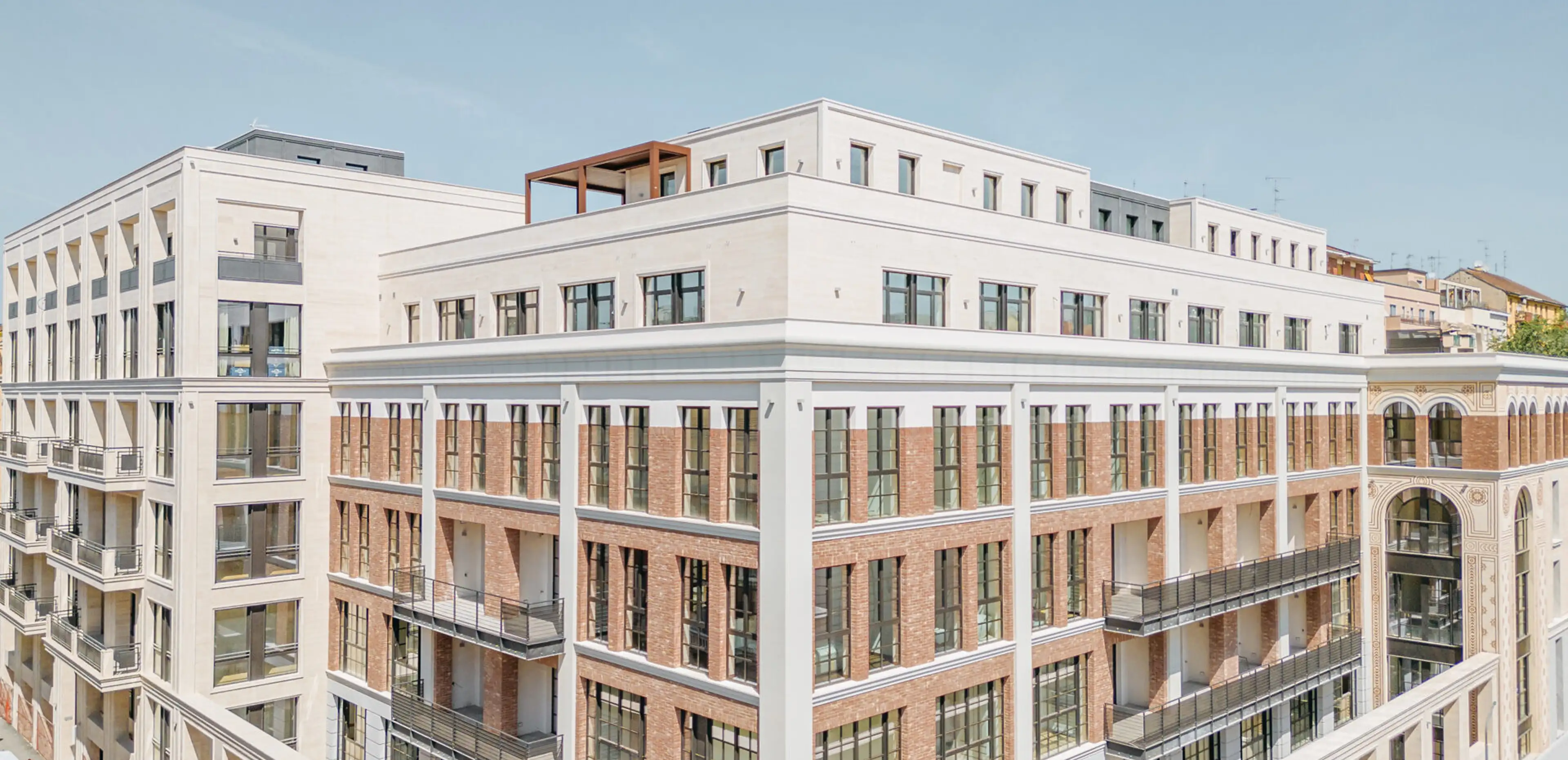 Vista aerea del Washington Building a Milano: riqualificazione di storica fabbrica nel quartiere Washington con elementi di facciata e decorazioni in Travertino Romano, cornicioni e lesene bianchi a contrasto con il mattone a vista - fornitura e posa in opera Trapattoni Marmi