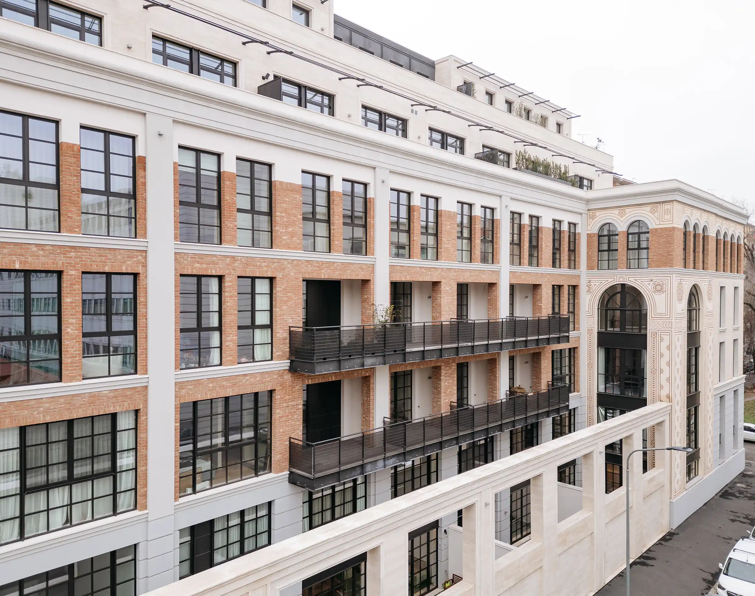 Vista aerea invernale del Washington Building nel quartiere Washington di Milano: complesso a isolato chiuso con facciata in Travertino Romano e mattone, pannelli fotovoltaici in copertura e terrazze - Trapattoni Marmi