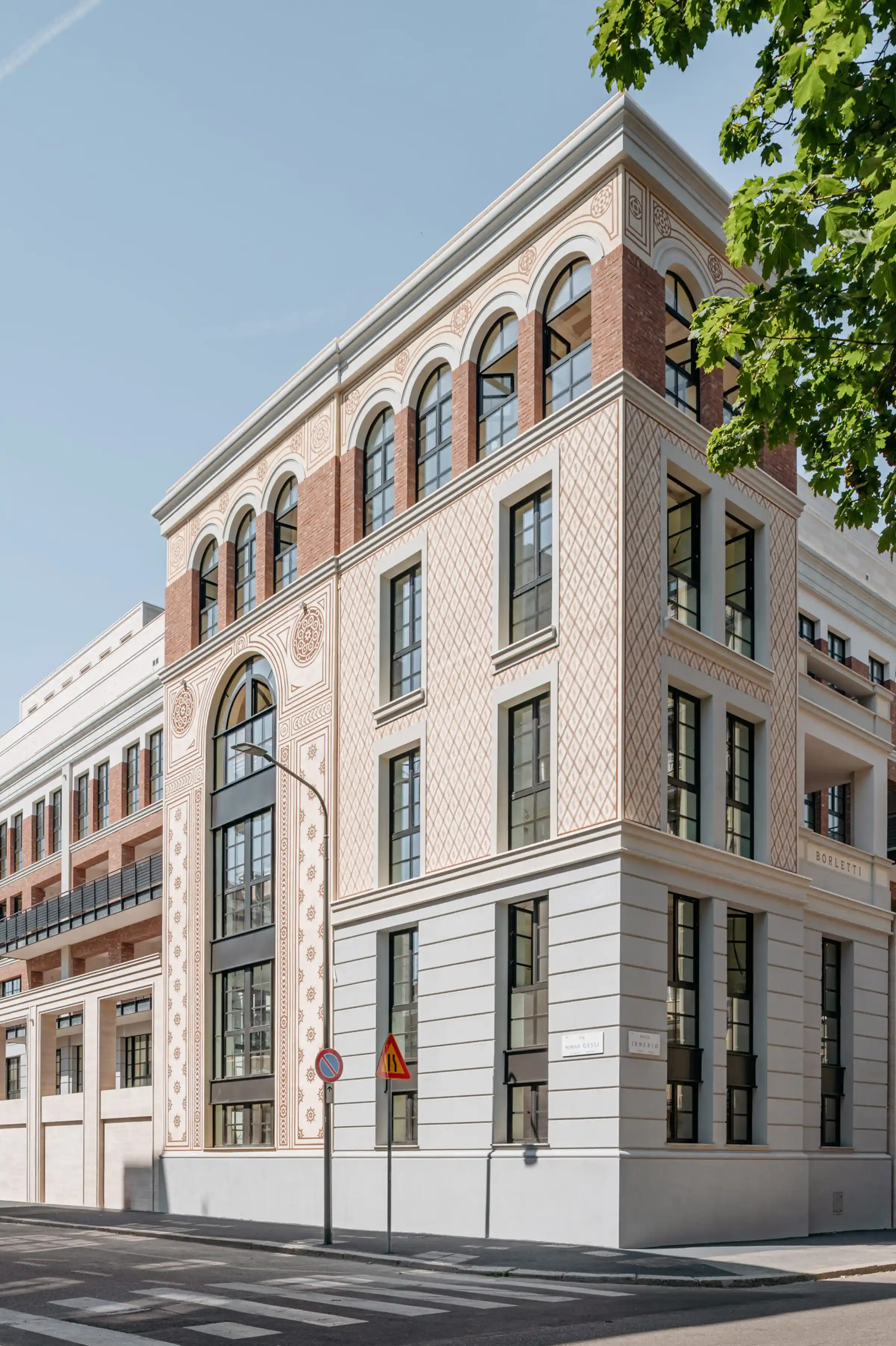 Facciata storica del Washington Building a Milano con decorazioni incise a motivi geometrici e floreali in Travertino Romano, archi a tutto sesto con cornici in pietra e torre d'angolo con loggiato - riqualificazione con fornitura e posa in opera Trapattoni Marmi