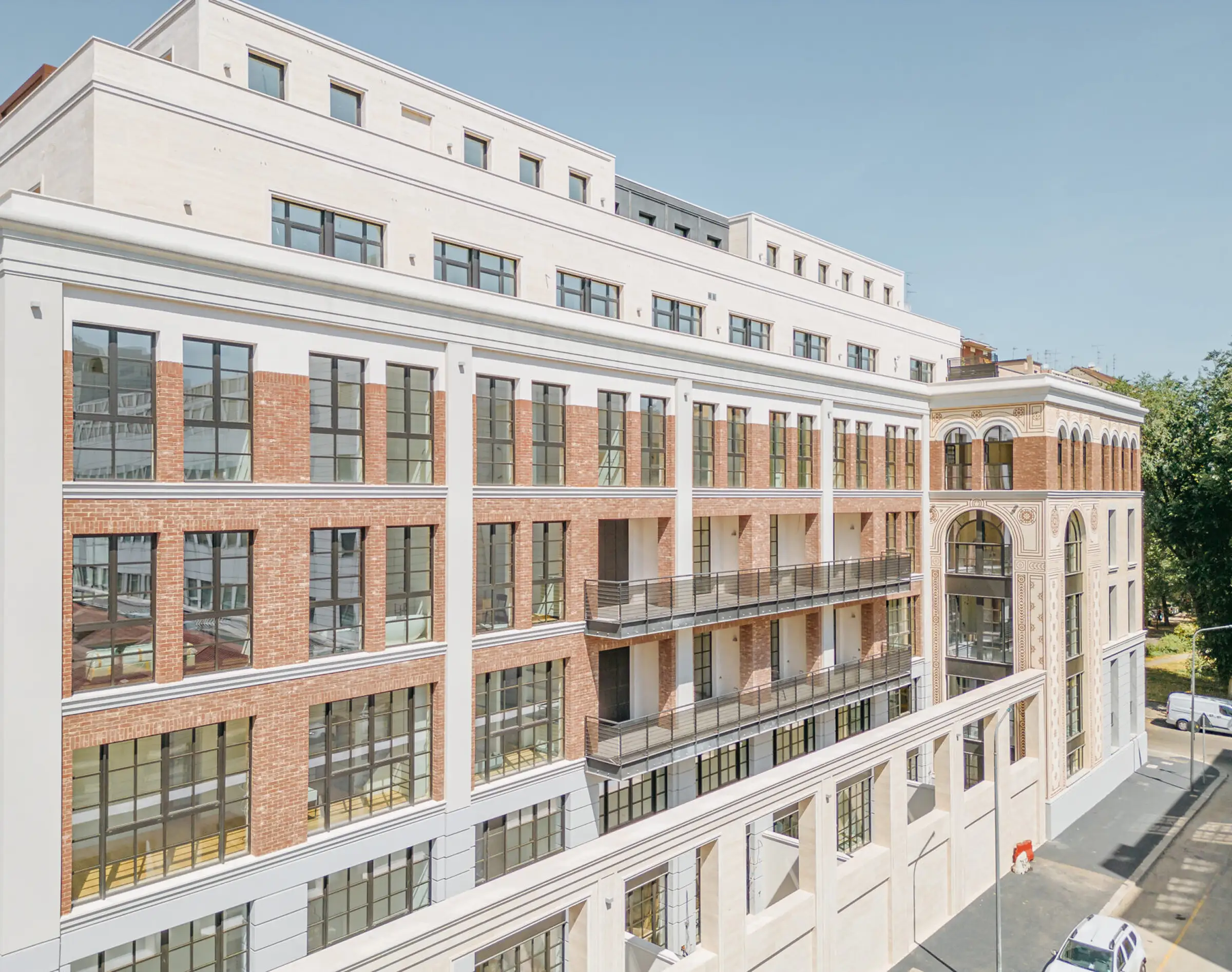 Prospetto laterale del Washington Building a Milano con loggiato ad arcate, rivestimento in mattone rosso, cornicioni e fasce marcapiano in Travertino Romano - riqualificazione di storica fabbrica nel quartiere Washington, Trapattoni Marmi