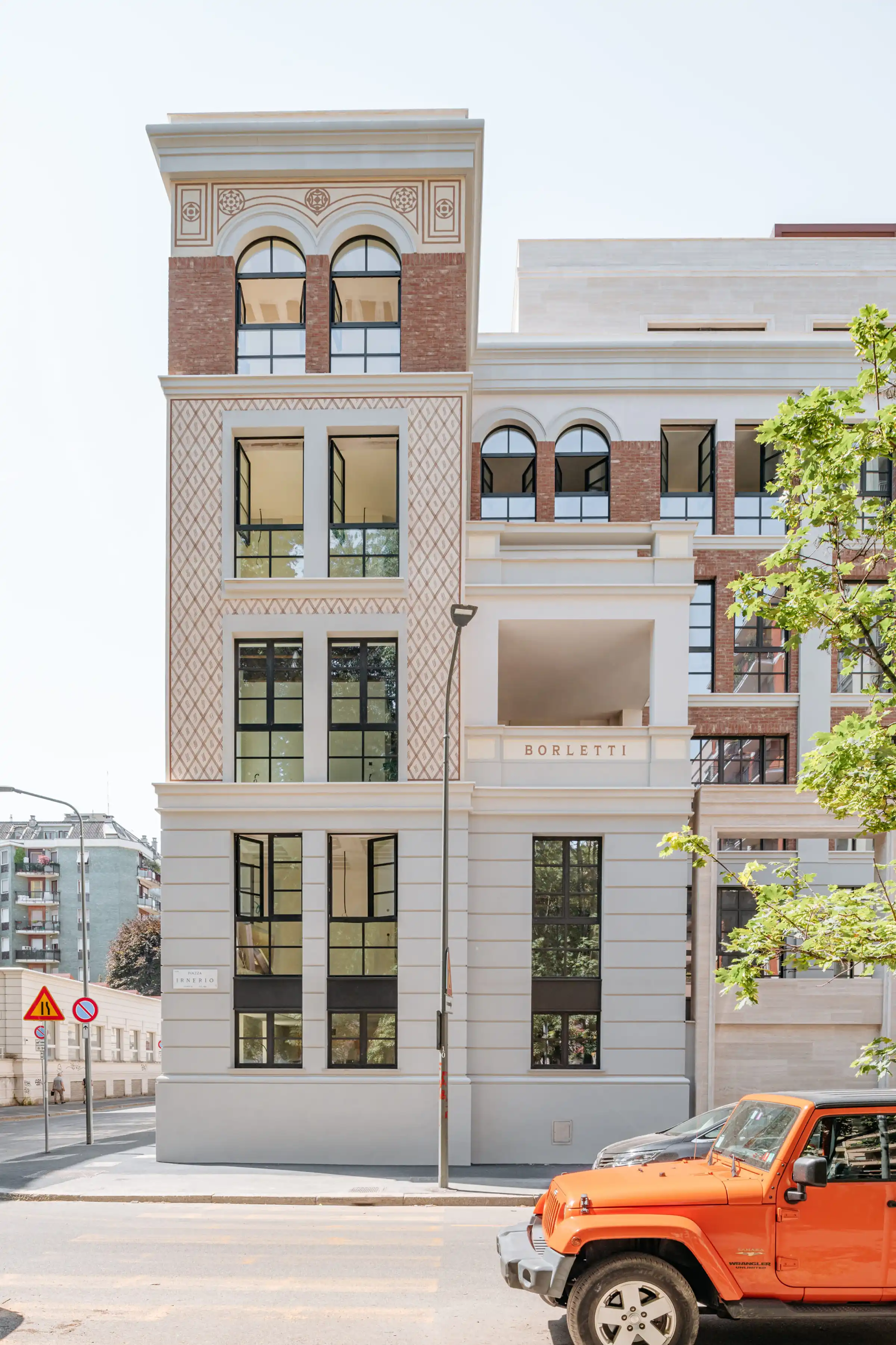 Torre Borletti del Washington Building a Milano: prospetto con decorazioni incise a motivi geometrici e fregi circolari in Travertino Romano, archi a tutto sesto con cornici in pietra, paramento in mattone rosso e insegna Borletti - riqualificazione storica fabbrica nel quartiere Washington, Trapattoni Marmi