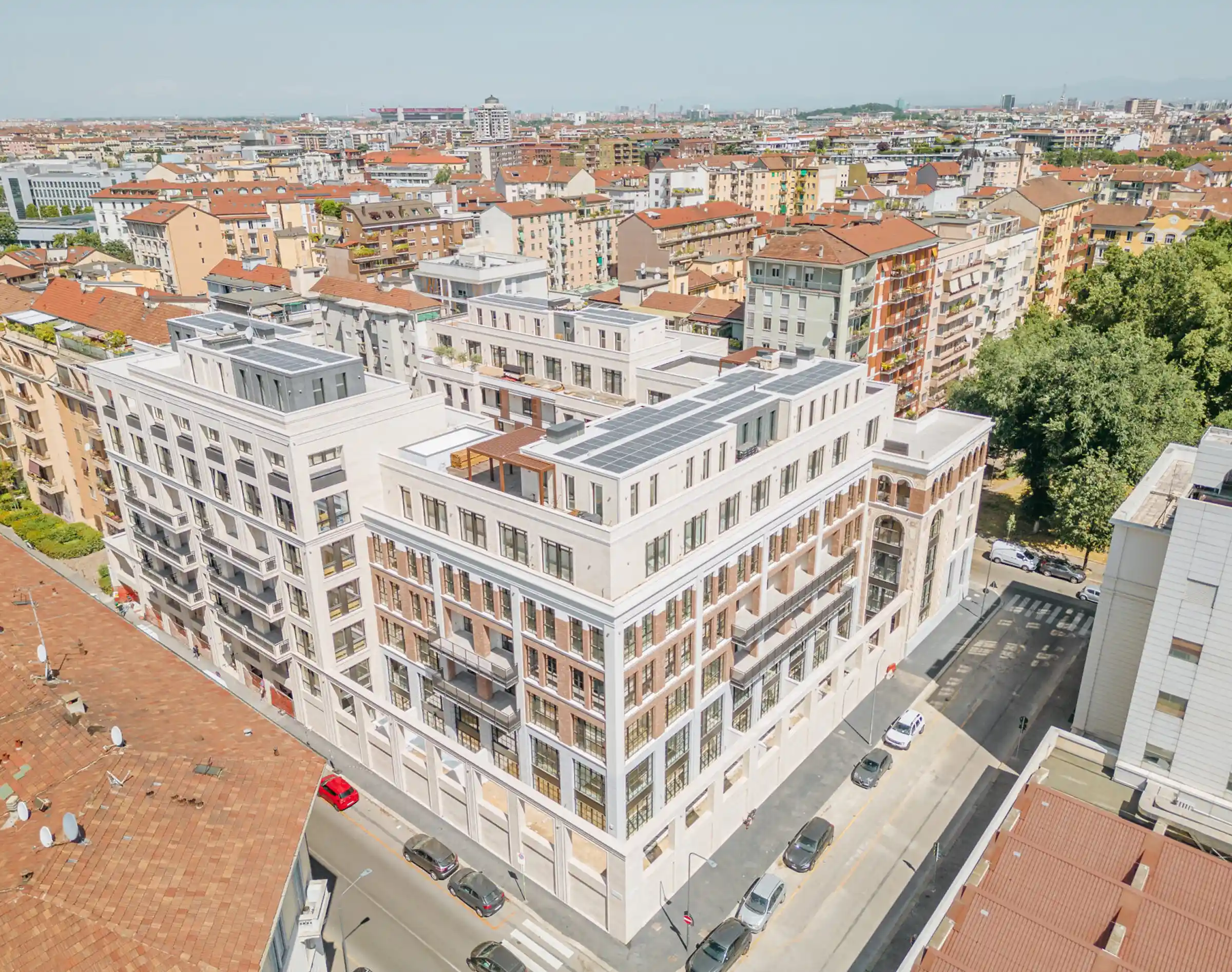 Vista aerea del Washington Building completato nel quartiere Washington di Milano: copertura con pannelli fotovoltaici, facciata in Travertino Romano e mattone a vista, volumi articolati con terrazze e penthouse - Trapattoni Marmi