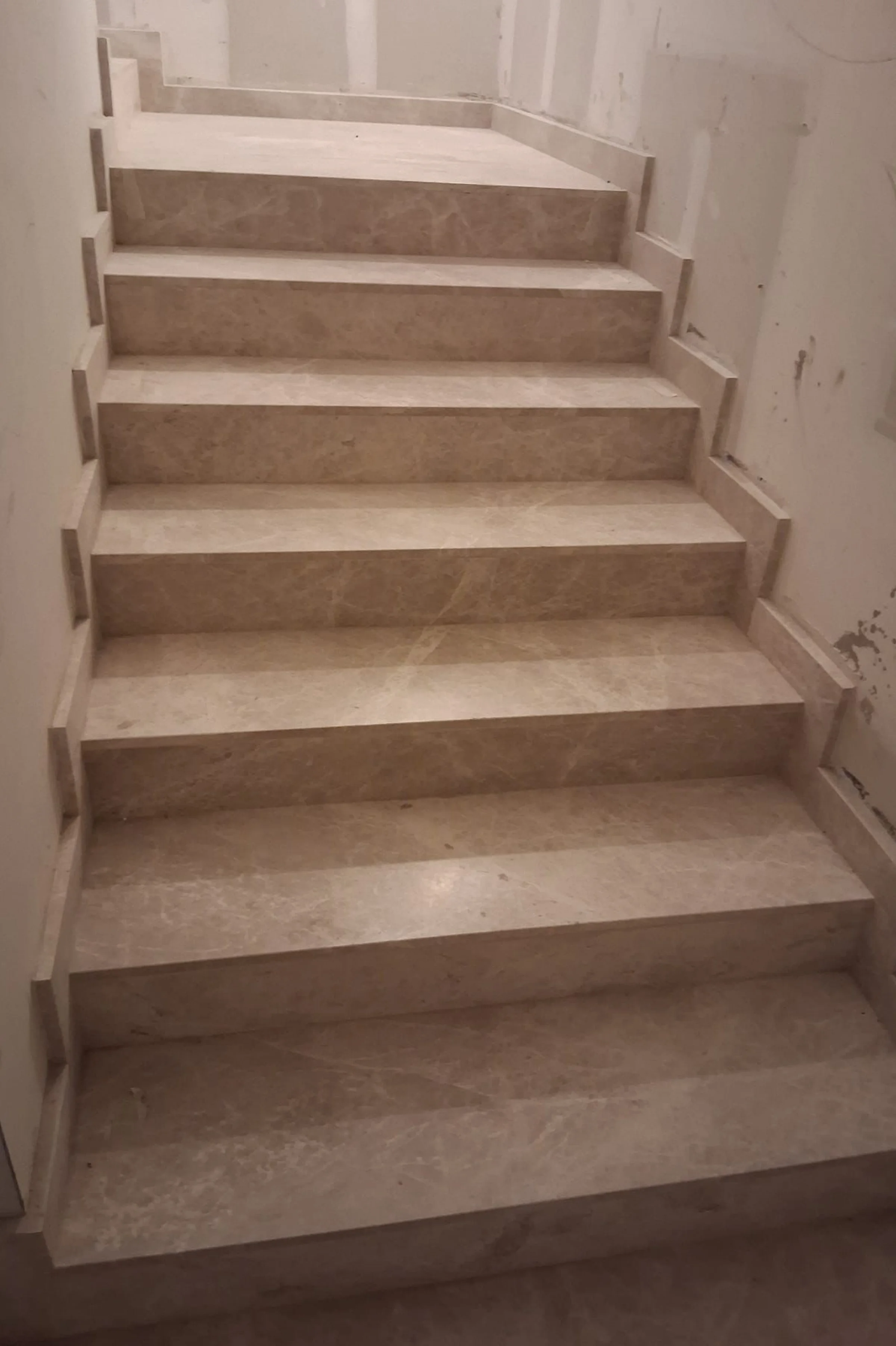 Scale comuni in Emperador White levigato in fase di posa in opera nel palazzo di Via Sassi a Milano - gradini e alzate in marmo grigio chiaro con venature bianche, lavorazione artigianale e posa in opera Trapattoni Marmi Bergamo