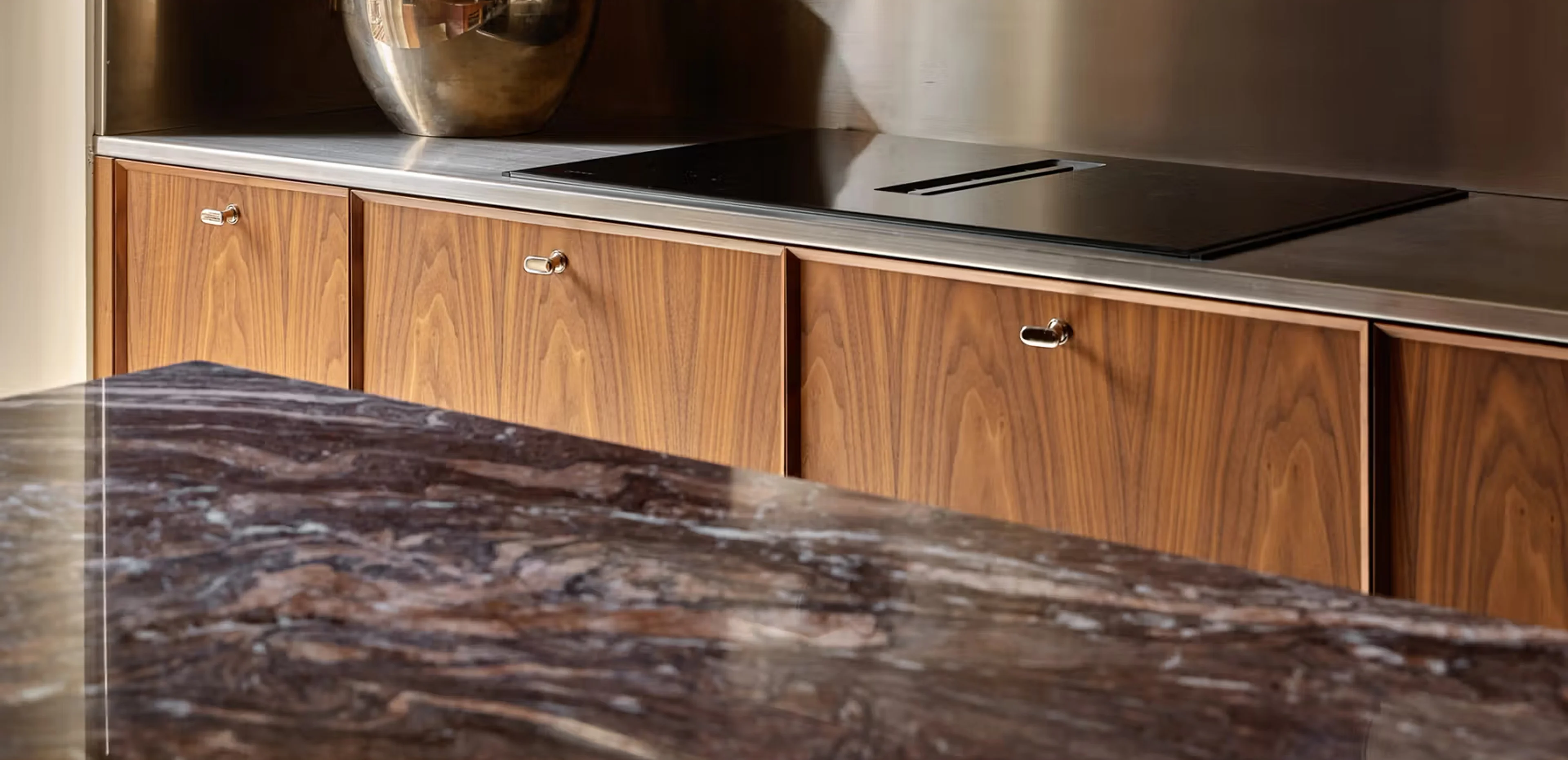 Dettaglio del piano cucina in Cipollino rosso-viola lucido con venature dinamiche a contrasto con i cassetti in noce Canaletto e maniglie in ottone - dimora privata di lusso ai Navigli di Milano, progetto LC Atelier di Lucrezia Calvi, lavorazione Trapattoni Marmi