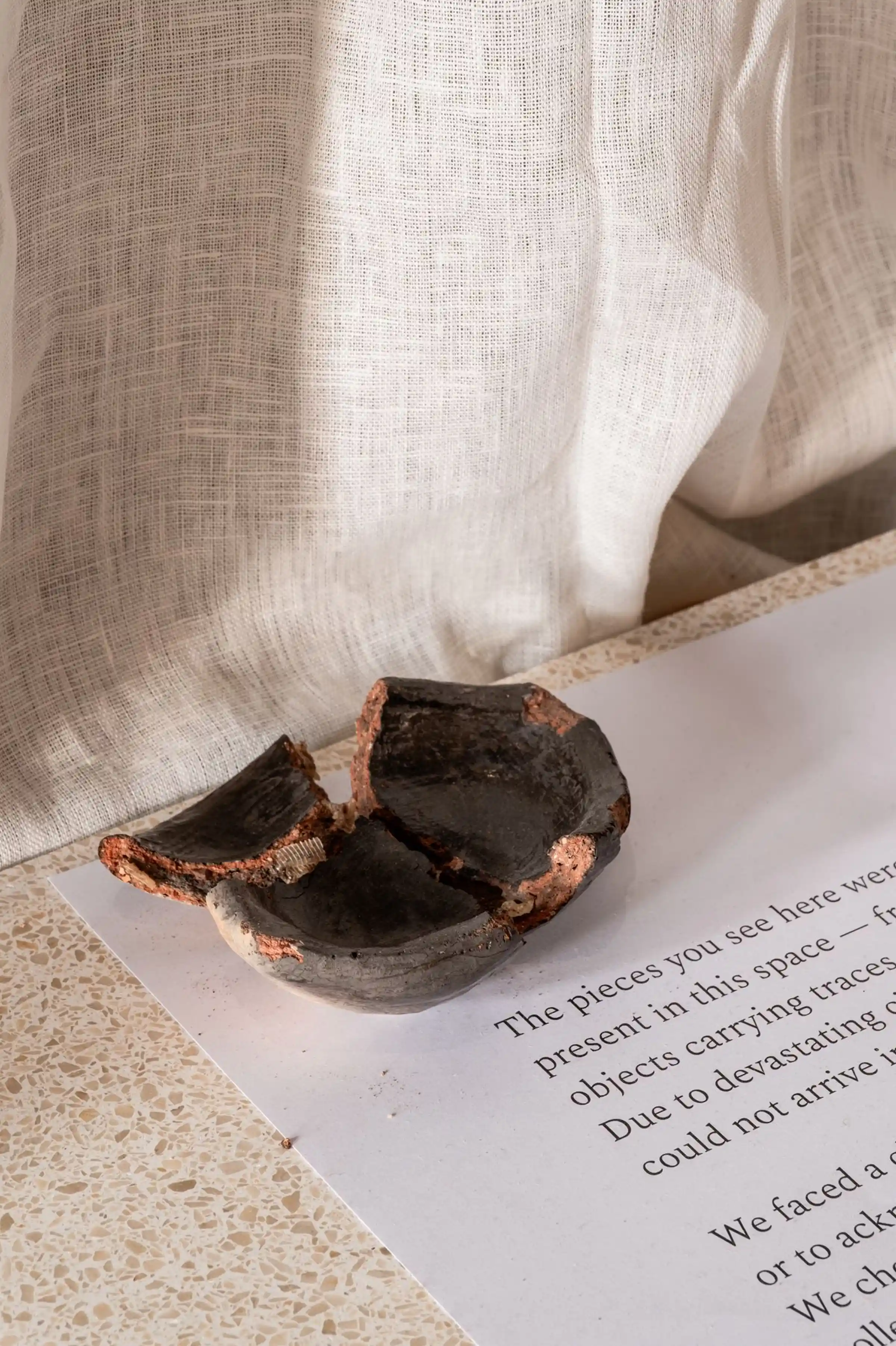 Dettaglio di frammento ceramico antico posato su piano in Agglotech SB210 Murano nell'installazione The Shape of What Remains - Biennale del Design di Venezia 2025 con il supporto di Trapattoni Marmi