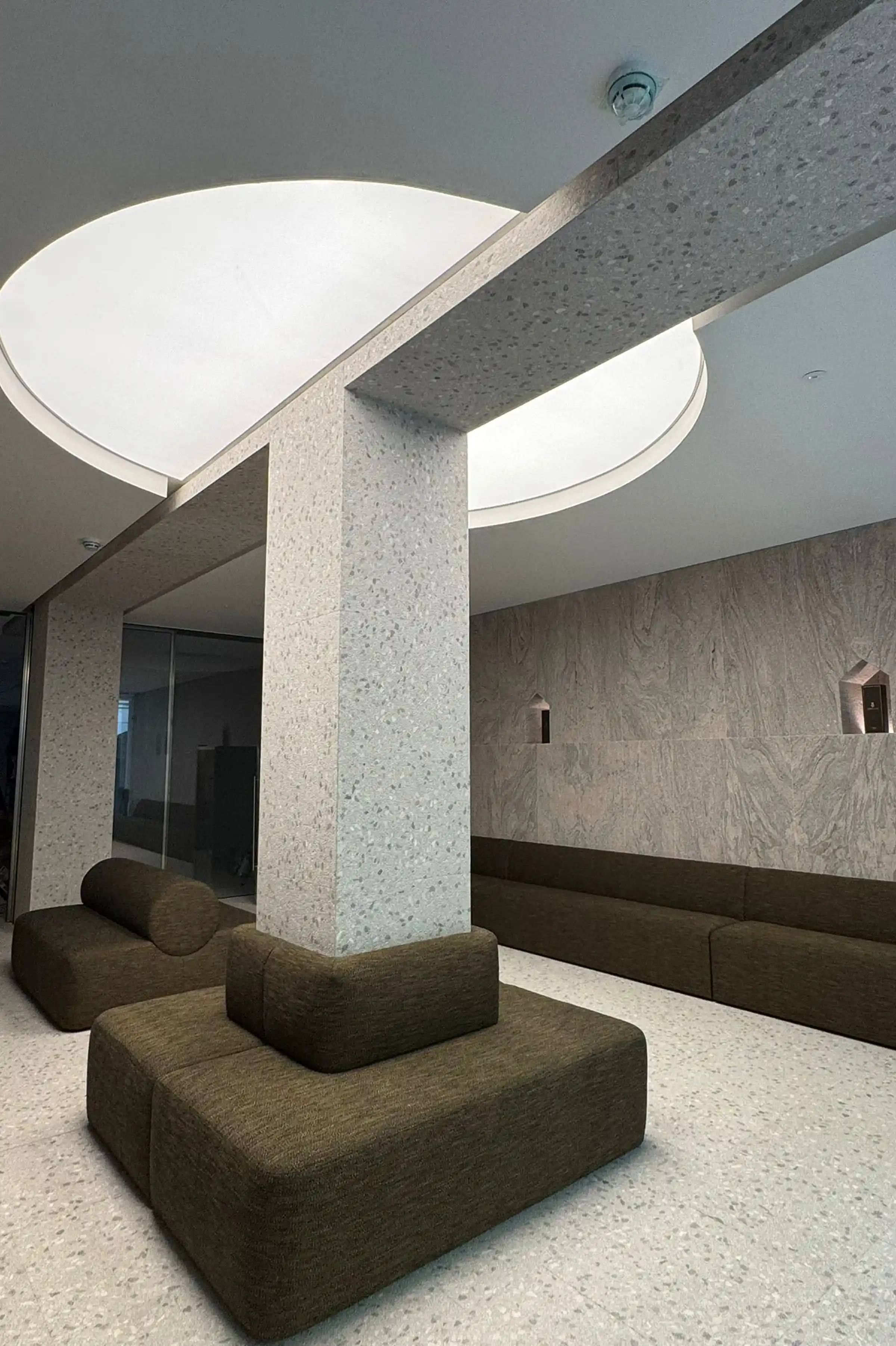 Vista d'insieme della lobby dello showroom Brera con colonna in Granito Juparanà Rosa e pavimento in Agglotech SB220 Giudecca con finitura sabbiata e spazzolata - fornitura e posa Trapattoni Marmi Milano