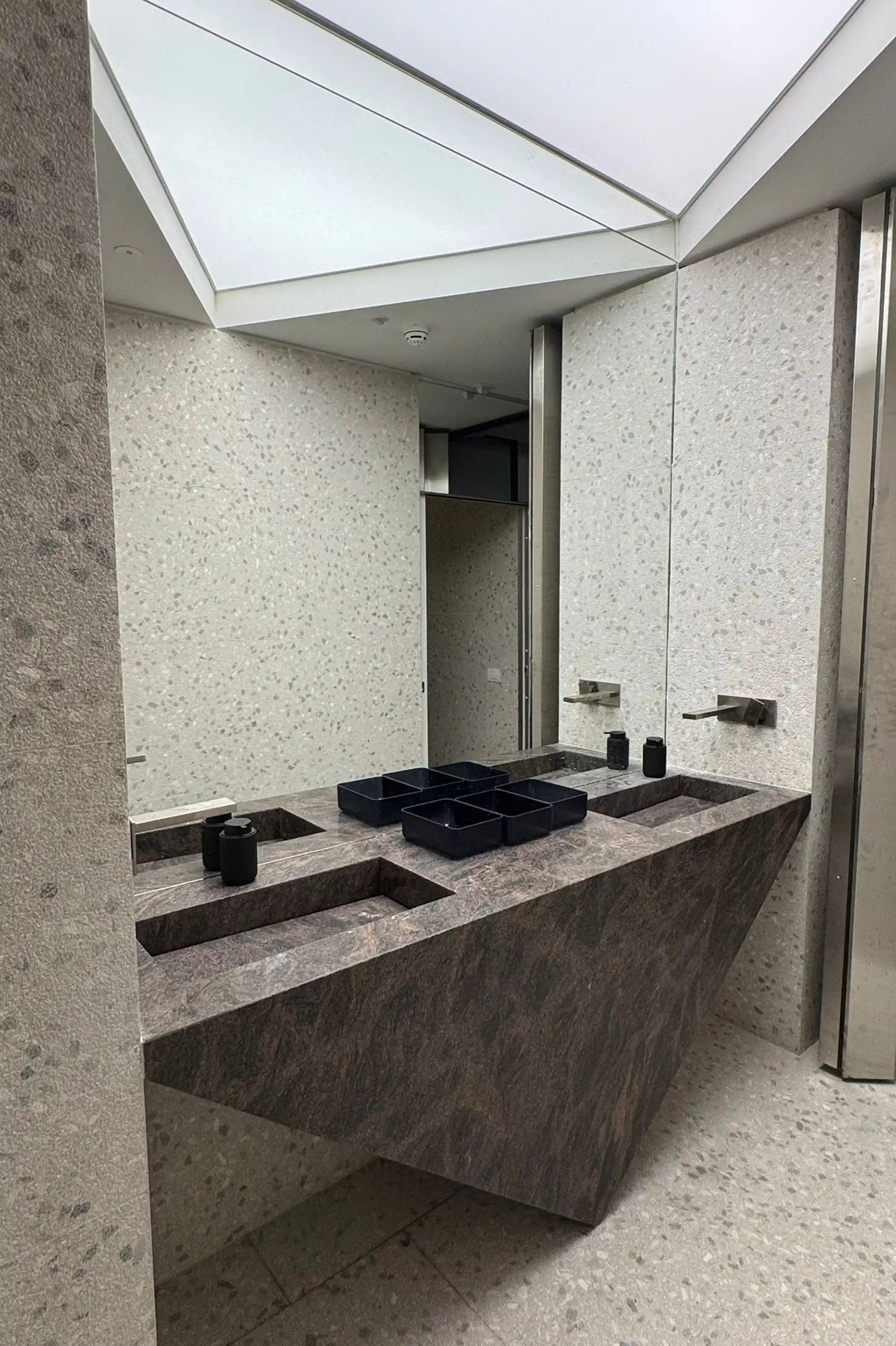 Lavandini monolitici di design in Granito Himalaya con piano a sbalzo e rivestimento a parete in Agglotech SB220 Giudecca nello showroom di Via Fiori Chiari a Milano - lavorazione Trapattoni Marmi