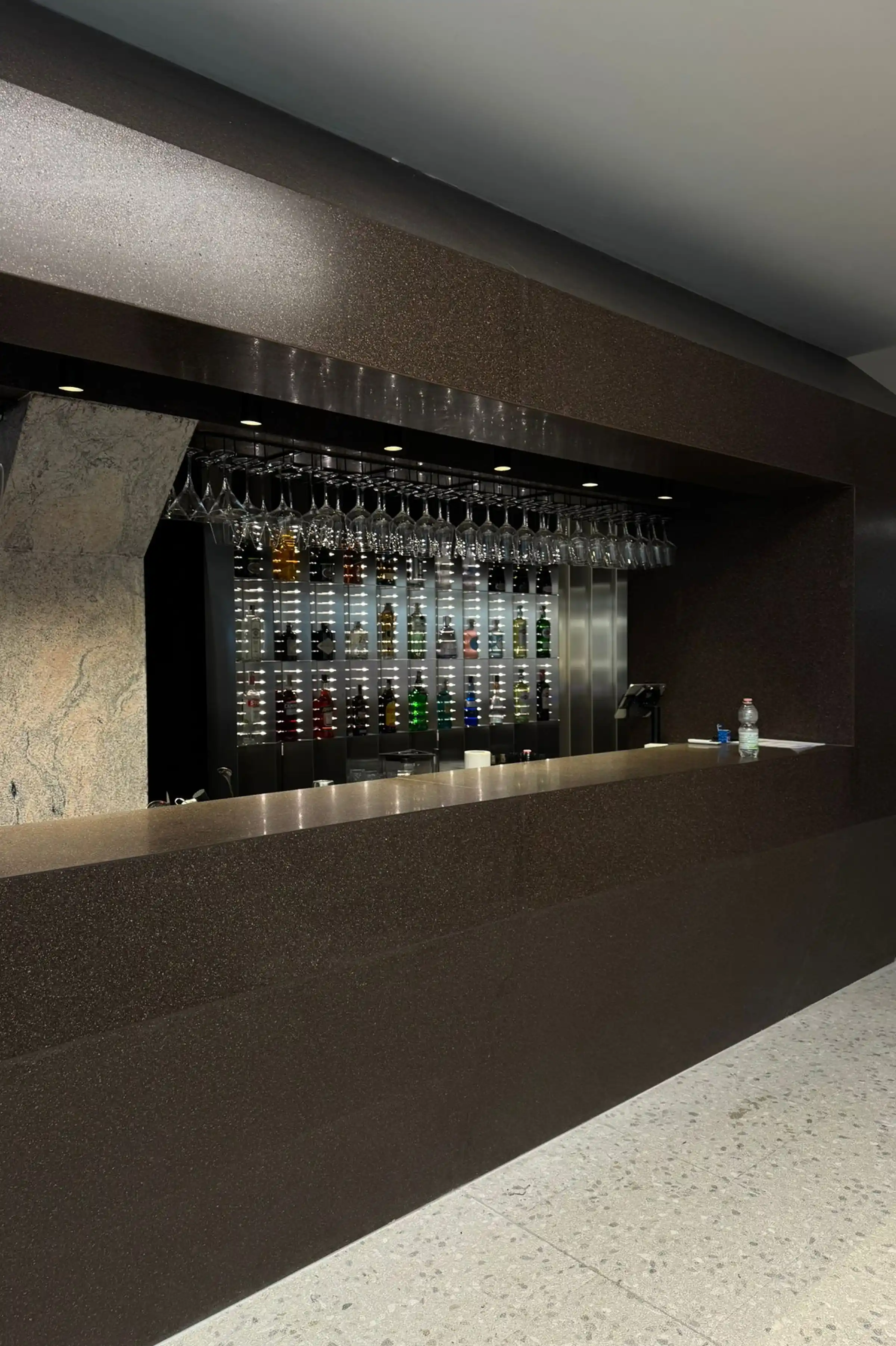 Bancone bar in Agglotech Profido con finitura scura a effetto granito e pavimento in Agglotech SB220 Giudecca nello showroom Brera in Via Fiori Chiari a Milano - Trapattoni Marmi