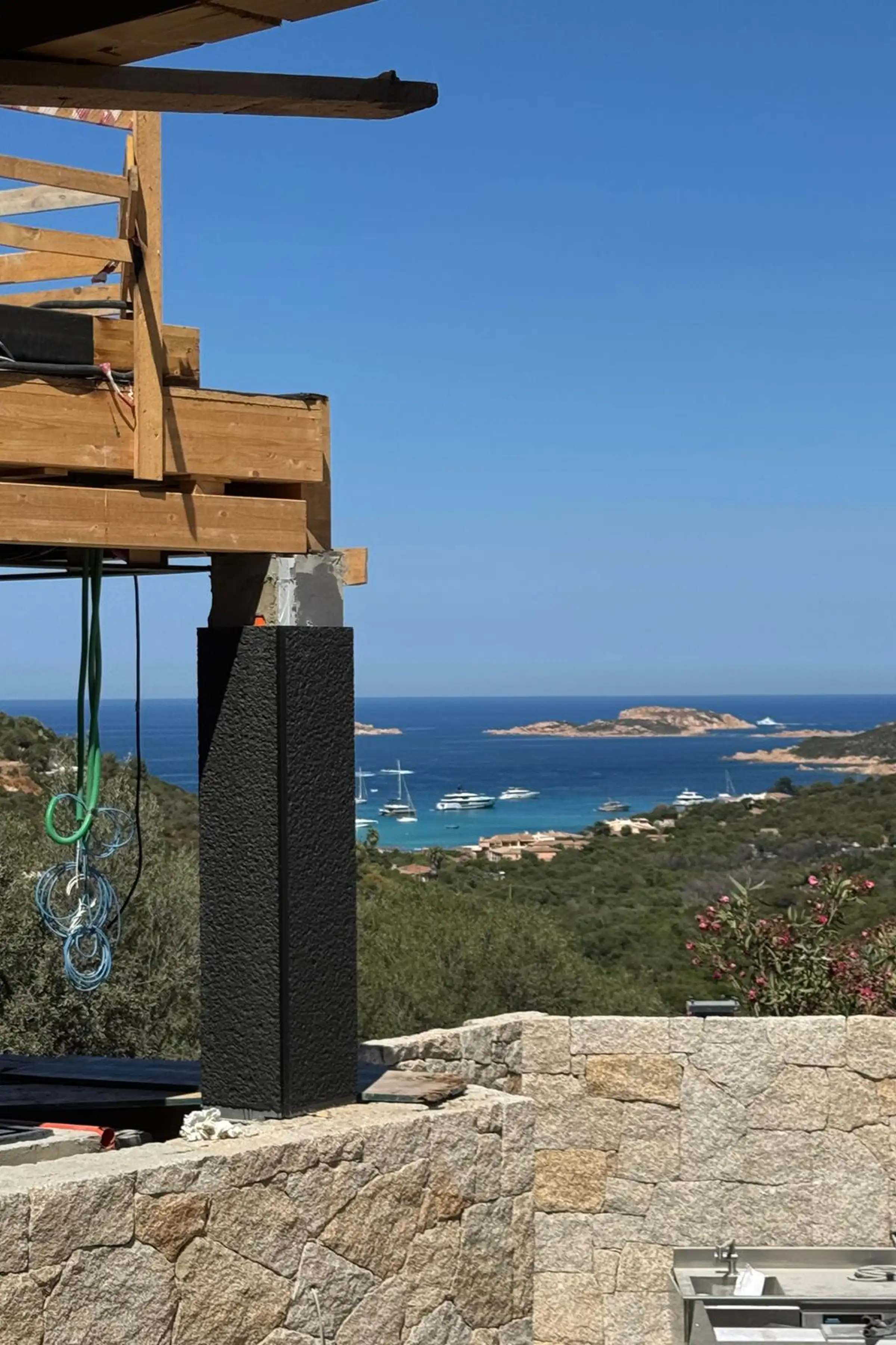 Pilastro rivestito in Nero Assoluto con lavorazione custom durante la fase di posa in opera con vista sulla baia di Porto Cervo in Costa Smeralda - Trapattoni Marmi