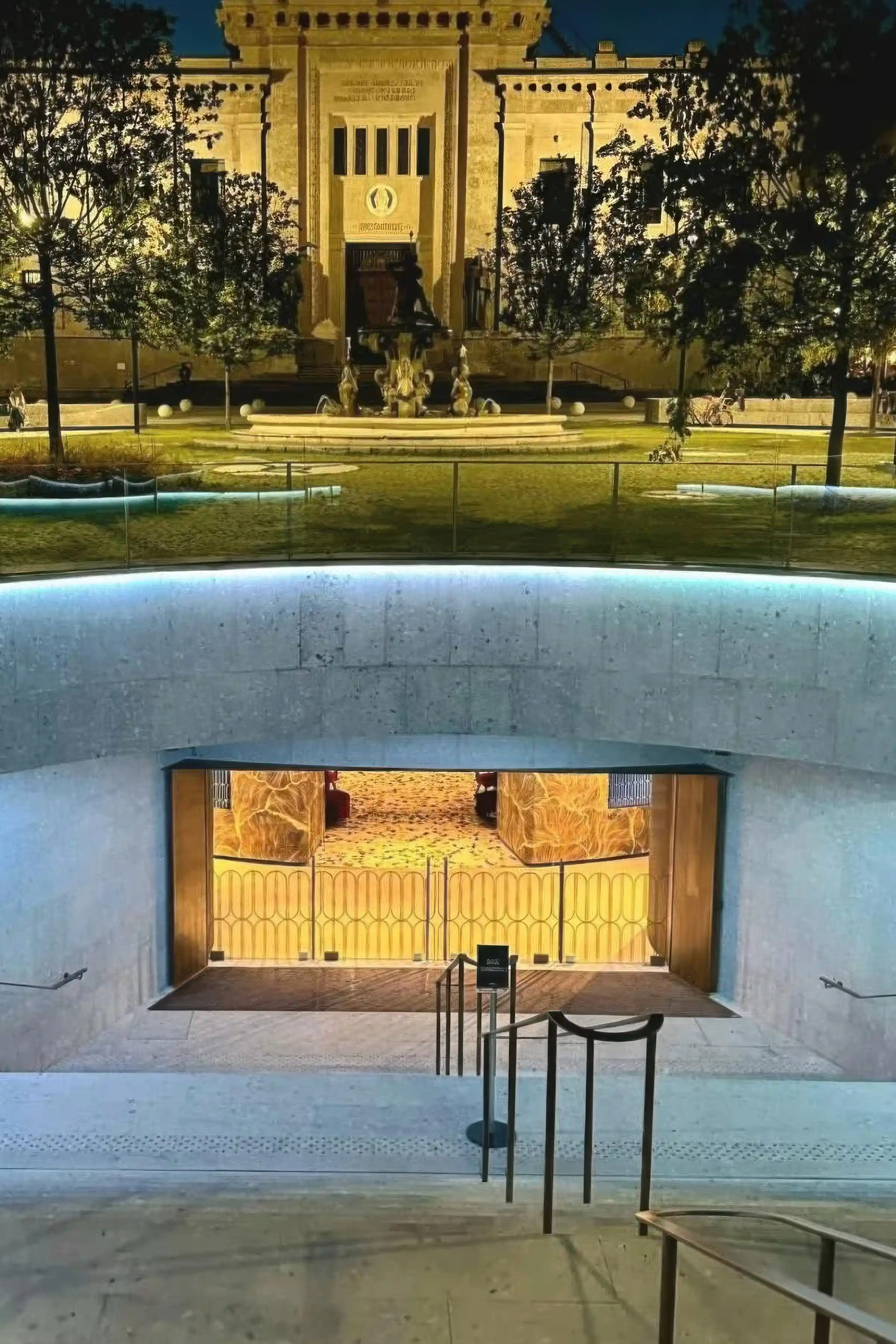 Vista notturna dell'ingresso seminterrato di Piazza Dante a Bergamo con rivestimento curvo in Agglotech SB130 Aggloceppo levigato e sabbiato - progetto di rinnovamento del Centro Piacentiniano Trapattoni Marmi