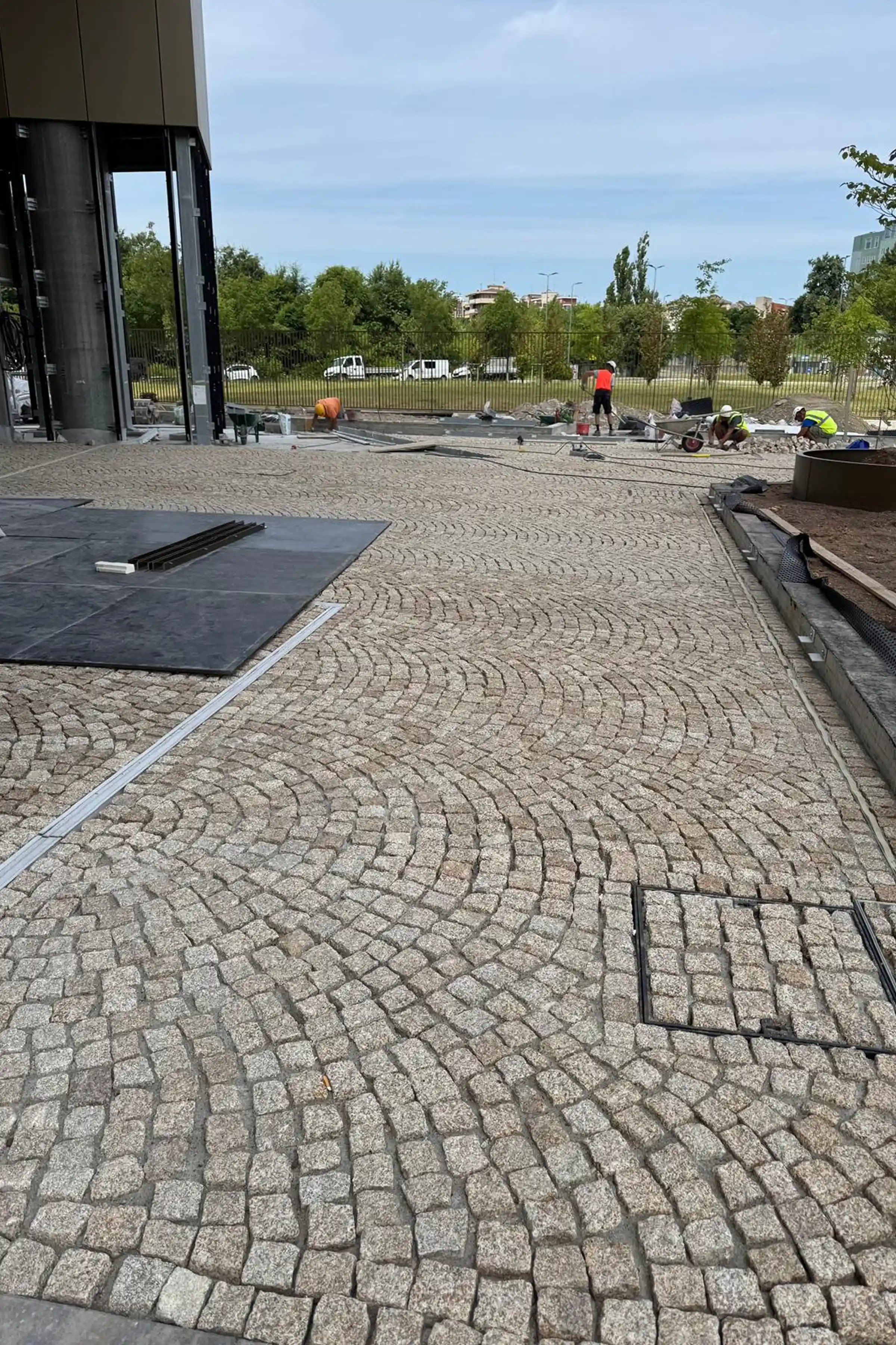 Posa in opera dei cubetti in Granito Giallo ad archi contrastanti nel giardino esterno della TheTris Tower a Famagosta Milano - lavorazione artigianale Trapattoni Marmi